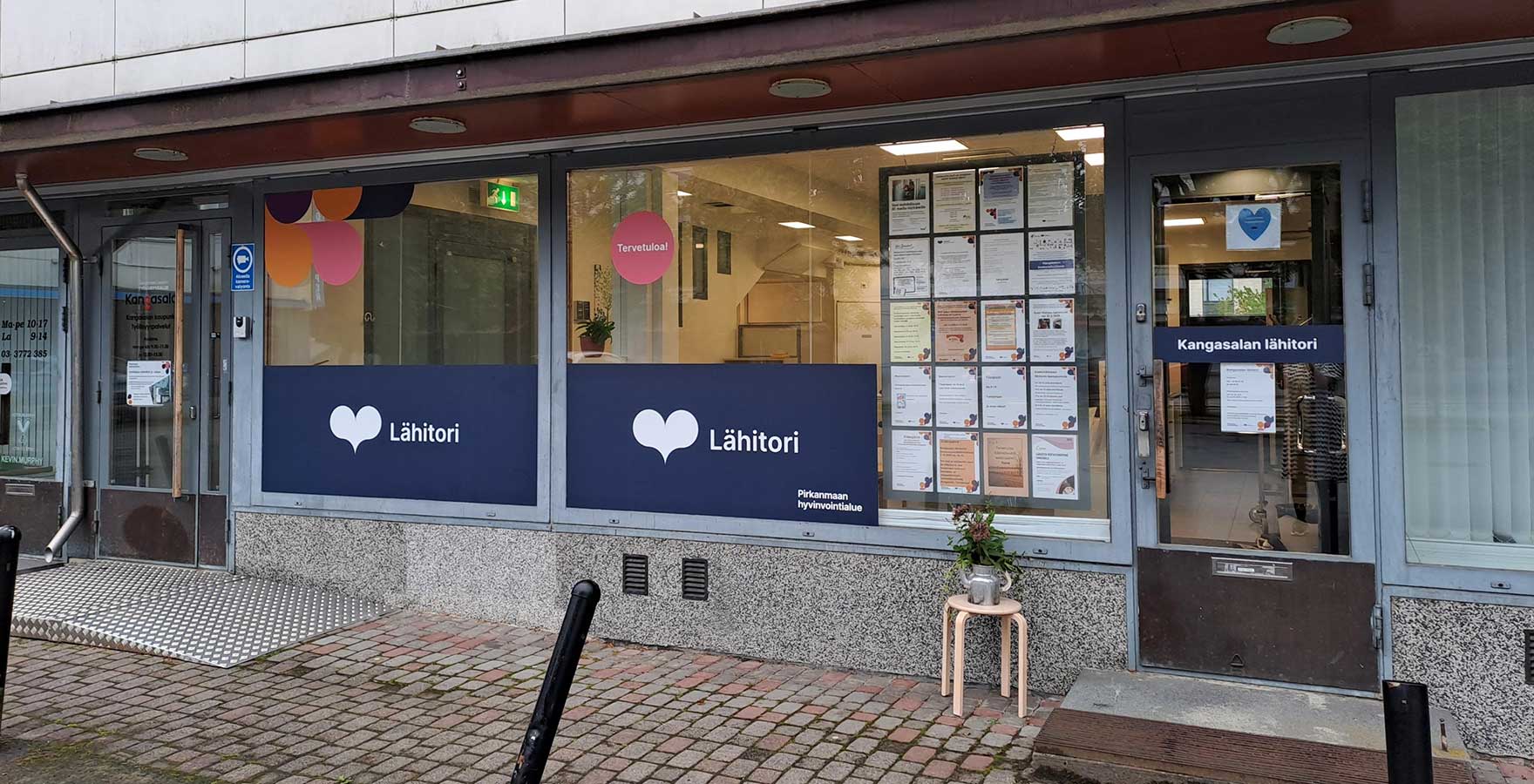 Kangasalan lähitorin etuovi ja ikkunat, joissa näkyy Pirkanmaan hyvinvointialuen teippauksia ja lähitorin ilmoituksia.