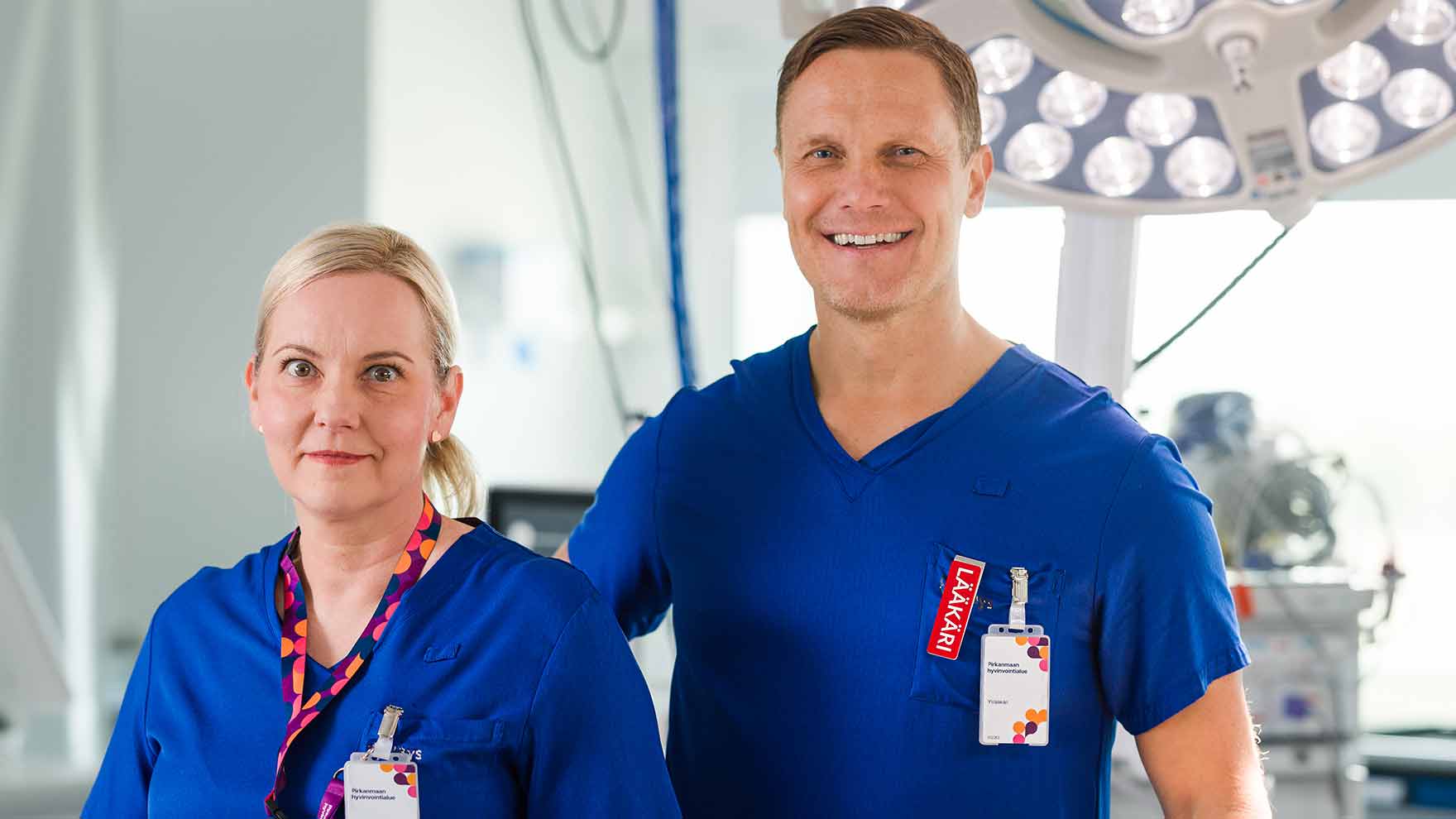 Kaksi sinivaatteista työntekijää seisoo leikkaussalissa.