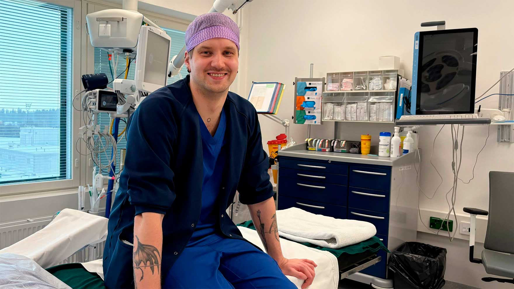 Oskari Puisto istuu toimenpidehuoneen pedillä ja hymyilee kameralle. 