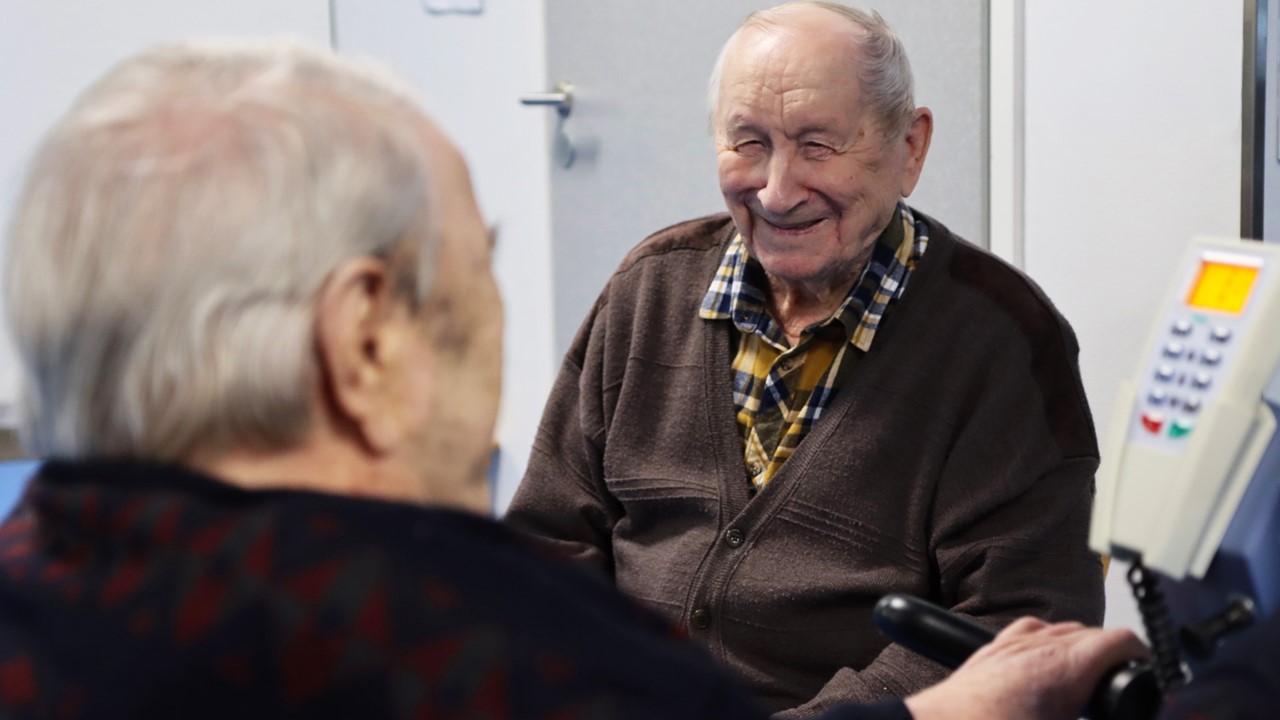 Kaksi ikäihmistä, joista toinen nauraa kohti kameraa.