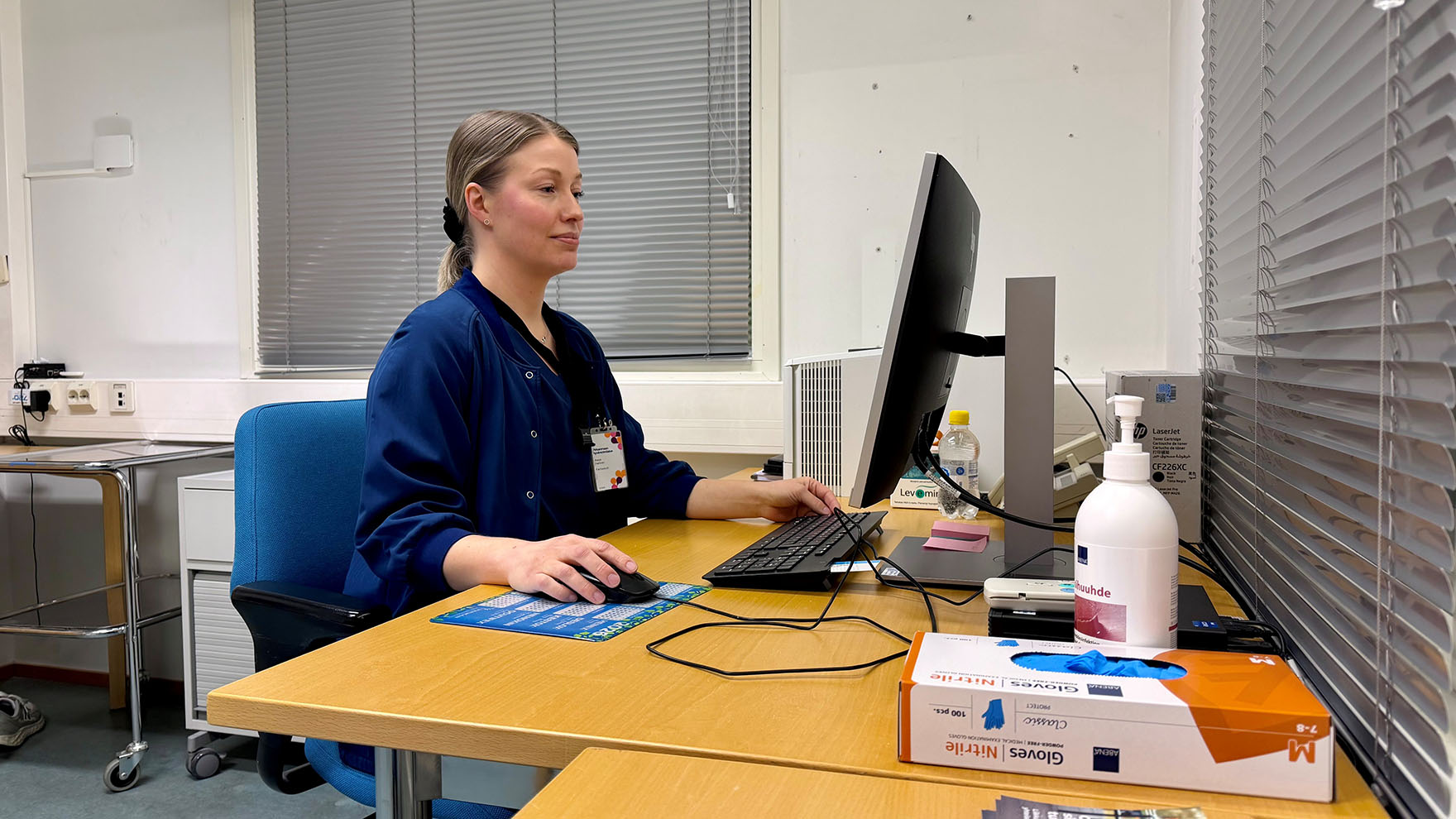 Farmaseutti Kaisa Hallinen istuu työpöydän ääressä ja katsoo tietokoneen näyttöä.