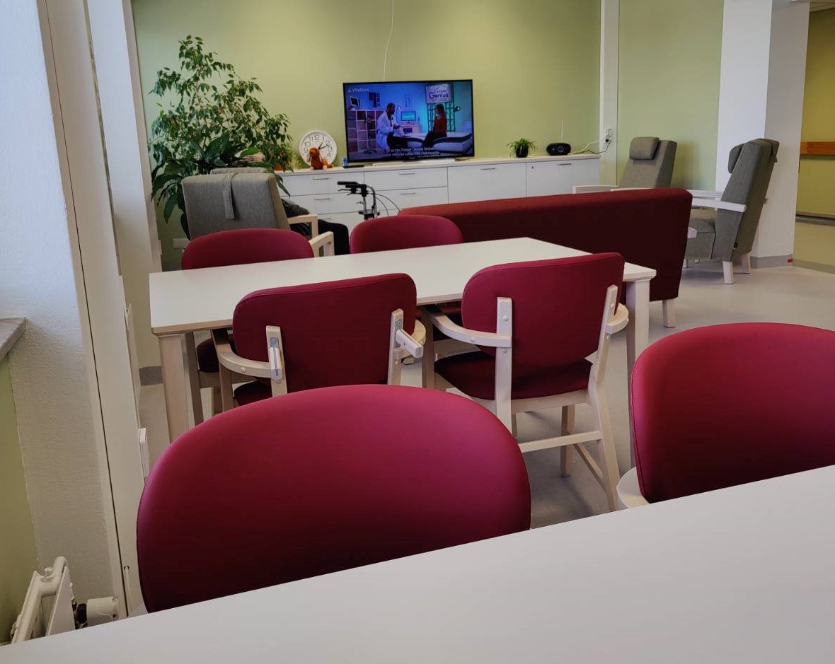 Uudessa VoiVa-yksikön oleskelutilassa on pöytiä, punaisia tuoleja ja televisio.