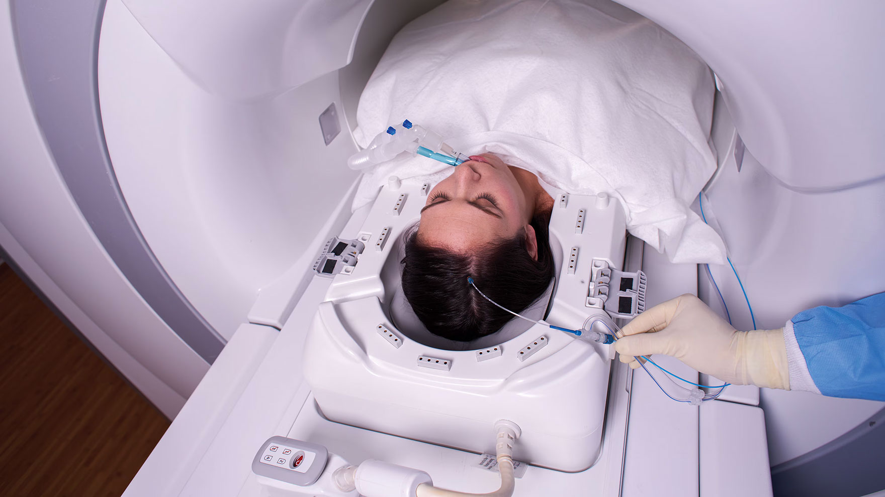 Nainen makaa magneettikuvauslaitteessa. Hänelle annetaan hoitoa päähän johdetun katetrin kautta.