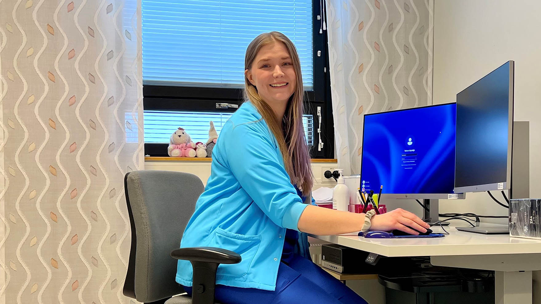 Sairaanhoitaja Sanni Vaskelainen istuu työpöydän ääressä vastaanottohuoneessa.