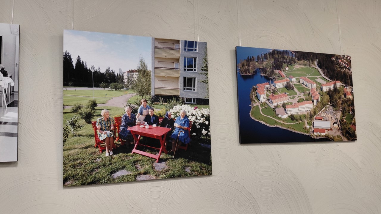 Seinällä on värillisiä valokuvatauluja Koukkuniemestä.