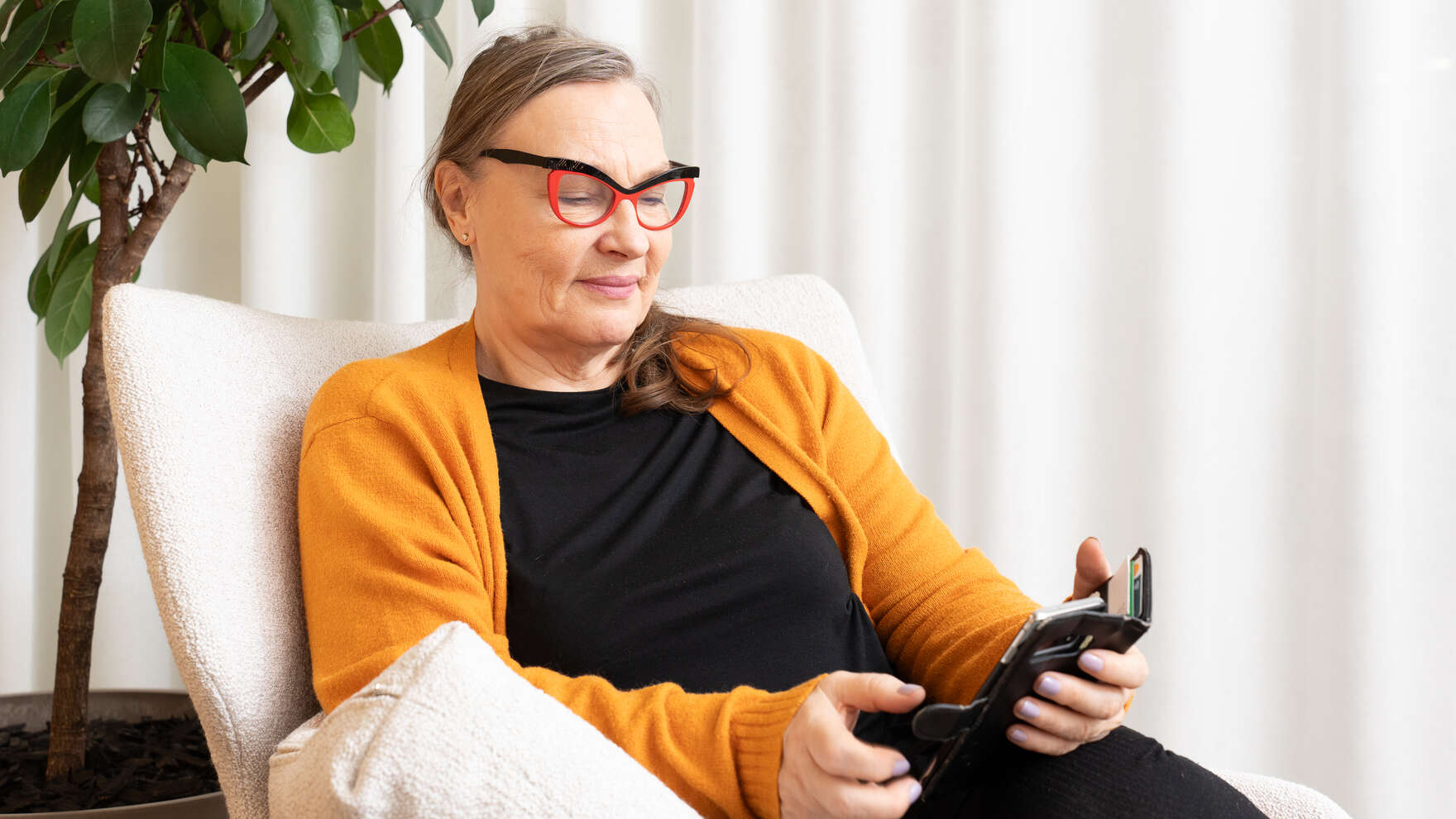 Henkilö nojatuolissa katsoo puhelinta.