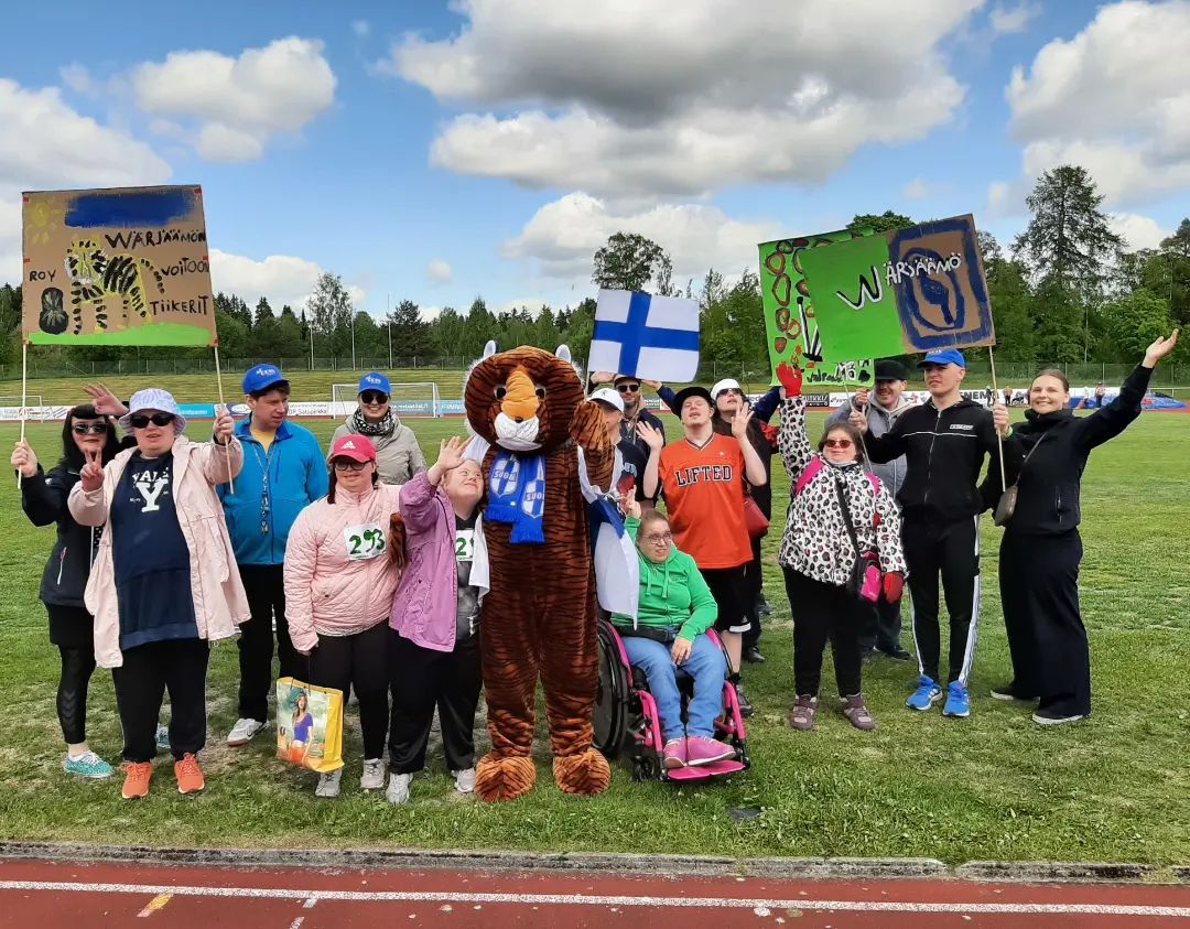 Kesäkisoihin osallistuneet poseeraavat kameraan urheilukentällä ruohikolla.