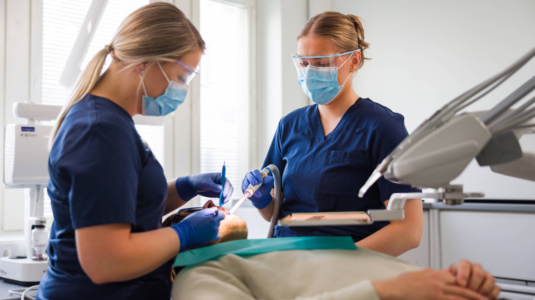 Hammaslääkäri ja hammashoitaja operoivat potilaan suuta.