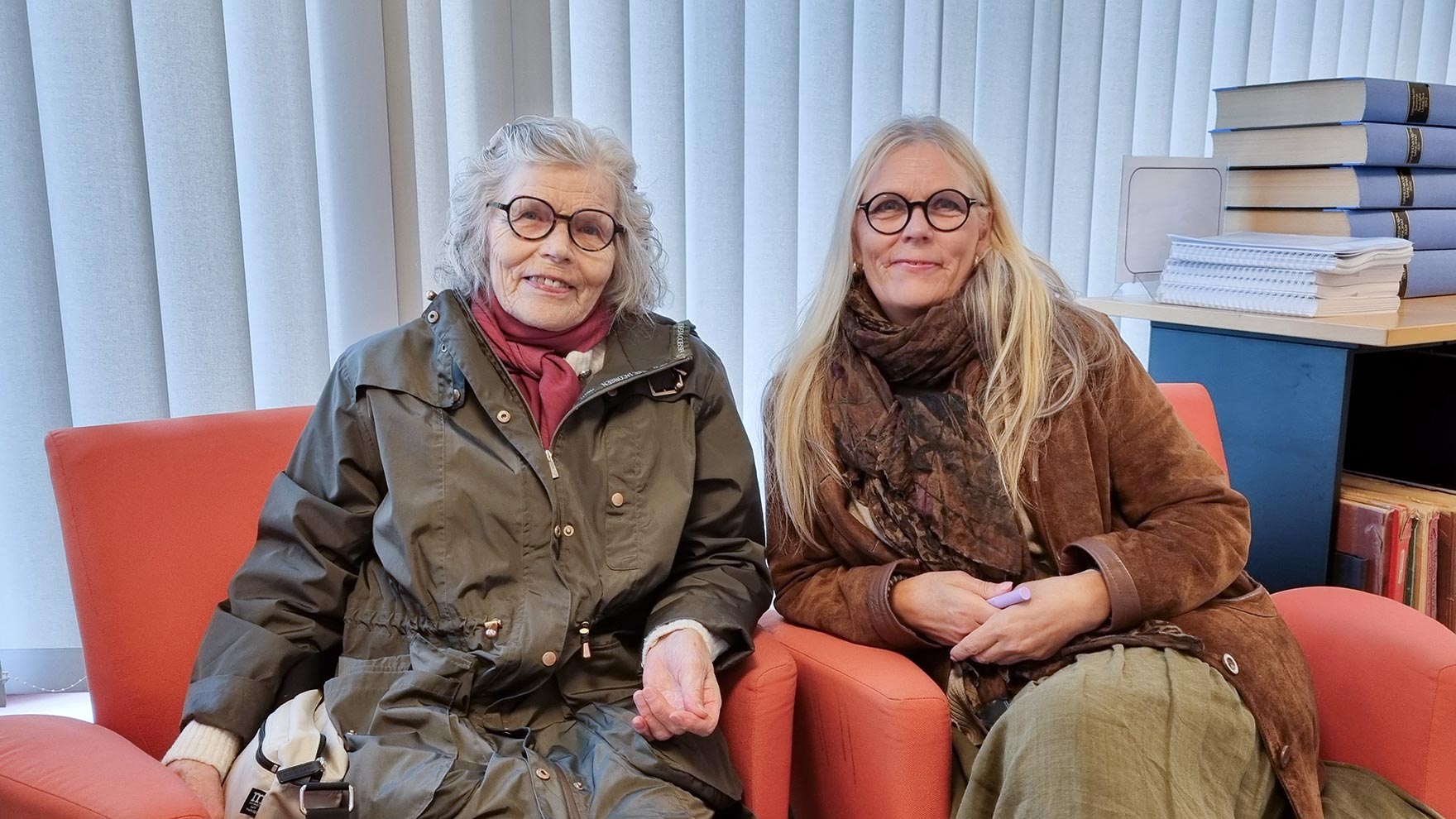Greta ja Ritva Lehtonen istuvat oransseilla nojatuoleilla ja katsovat hymyillen kameraan.
