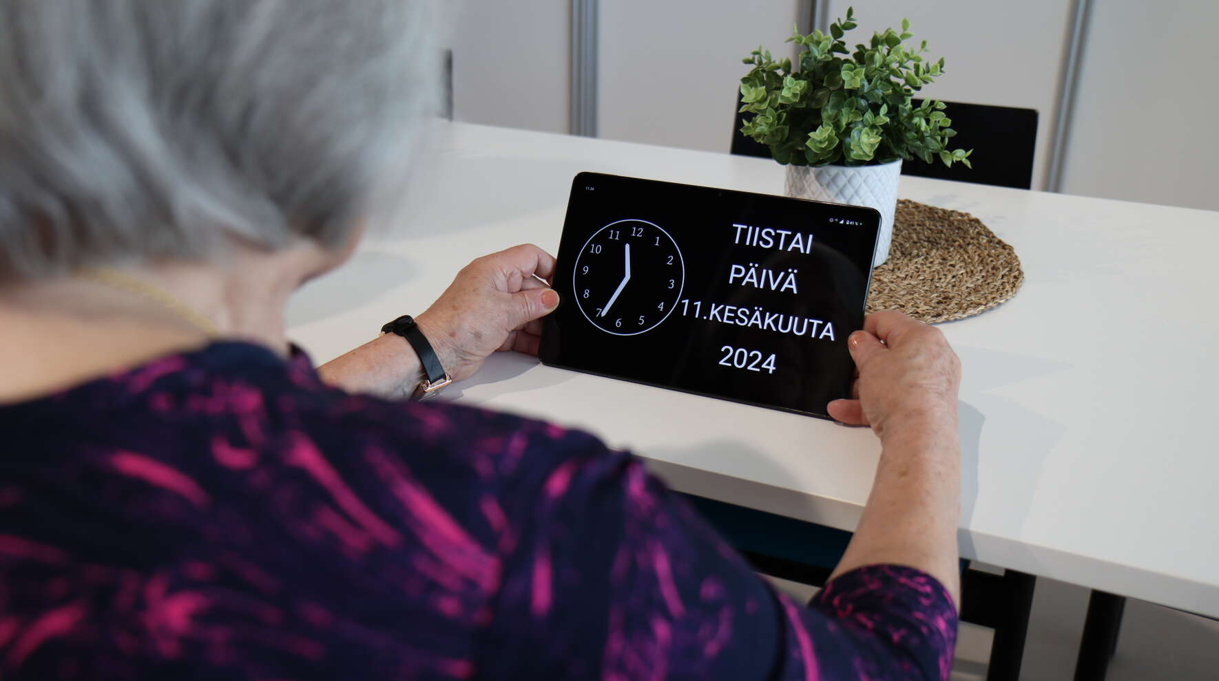 Ikäihminen katsoo laitetta, jossa näkyy kellonaika ja päivämäärä.