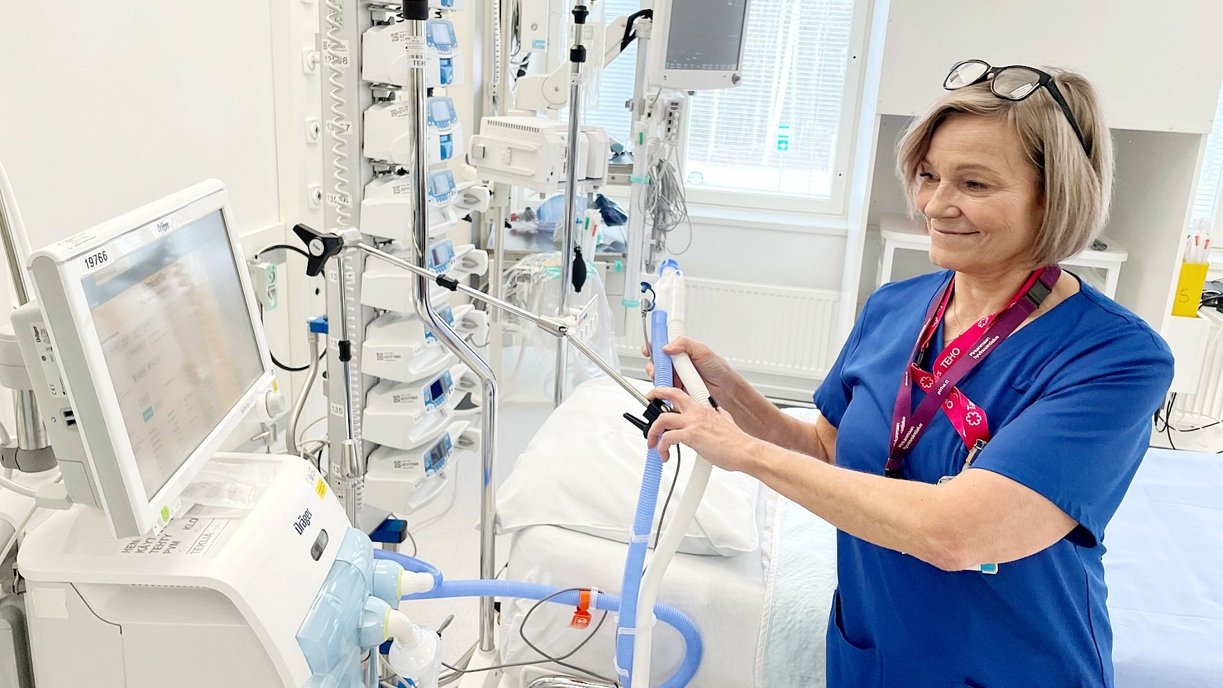 Sari Vierre tehohoitohuoneessa, jossa on potilassänky ja erilaisia tehohoitoon liittyviä laitteita.
