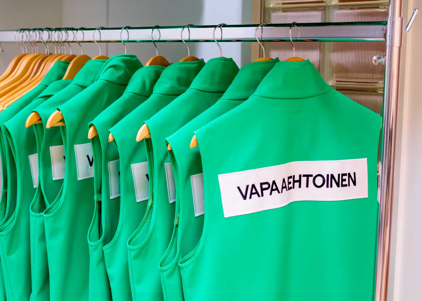 Vihreitä vapaaehtoisliivejä henkarissa.