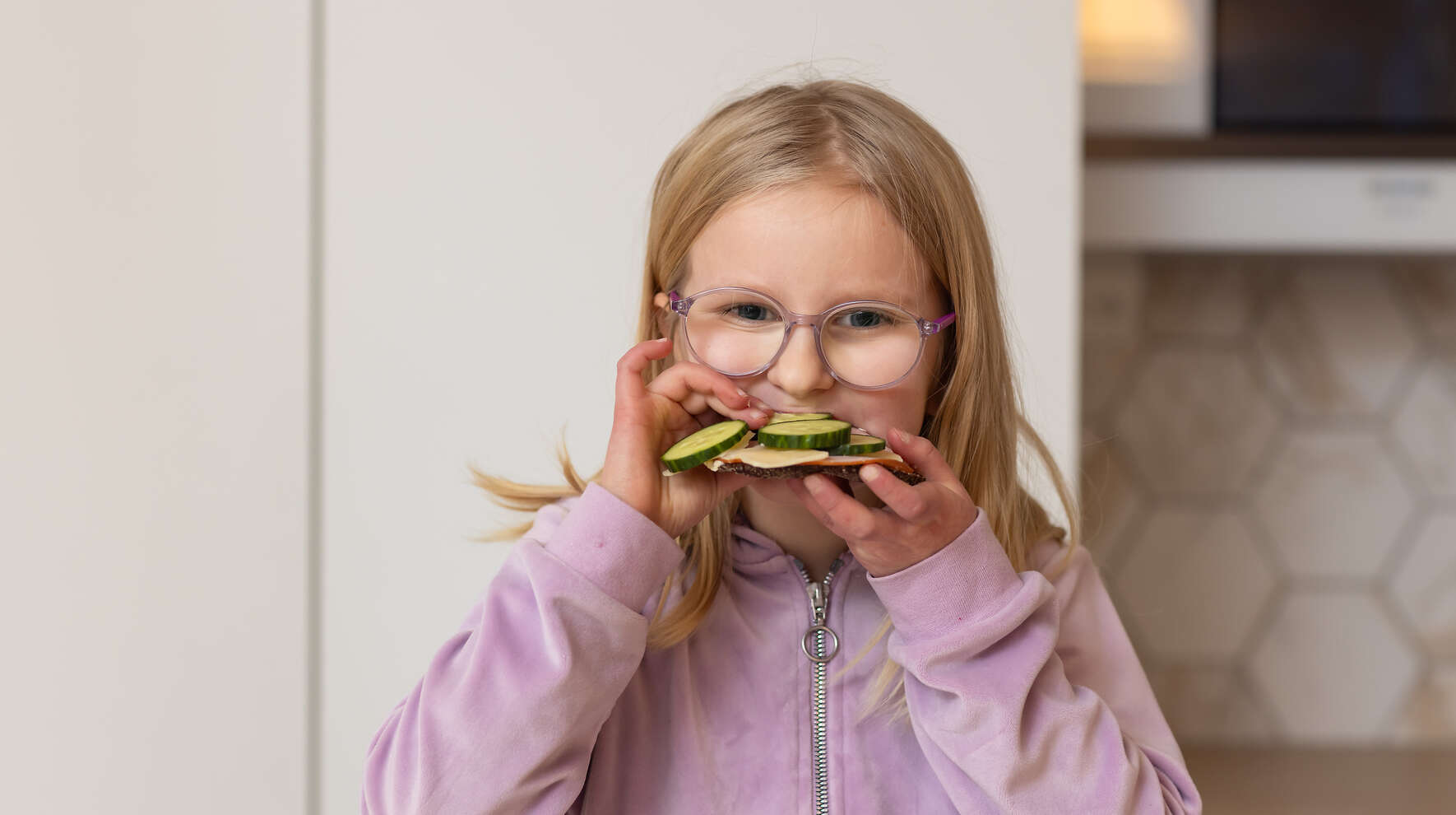 Kouluikäinen lapsi haukkaa voileipää.