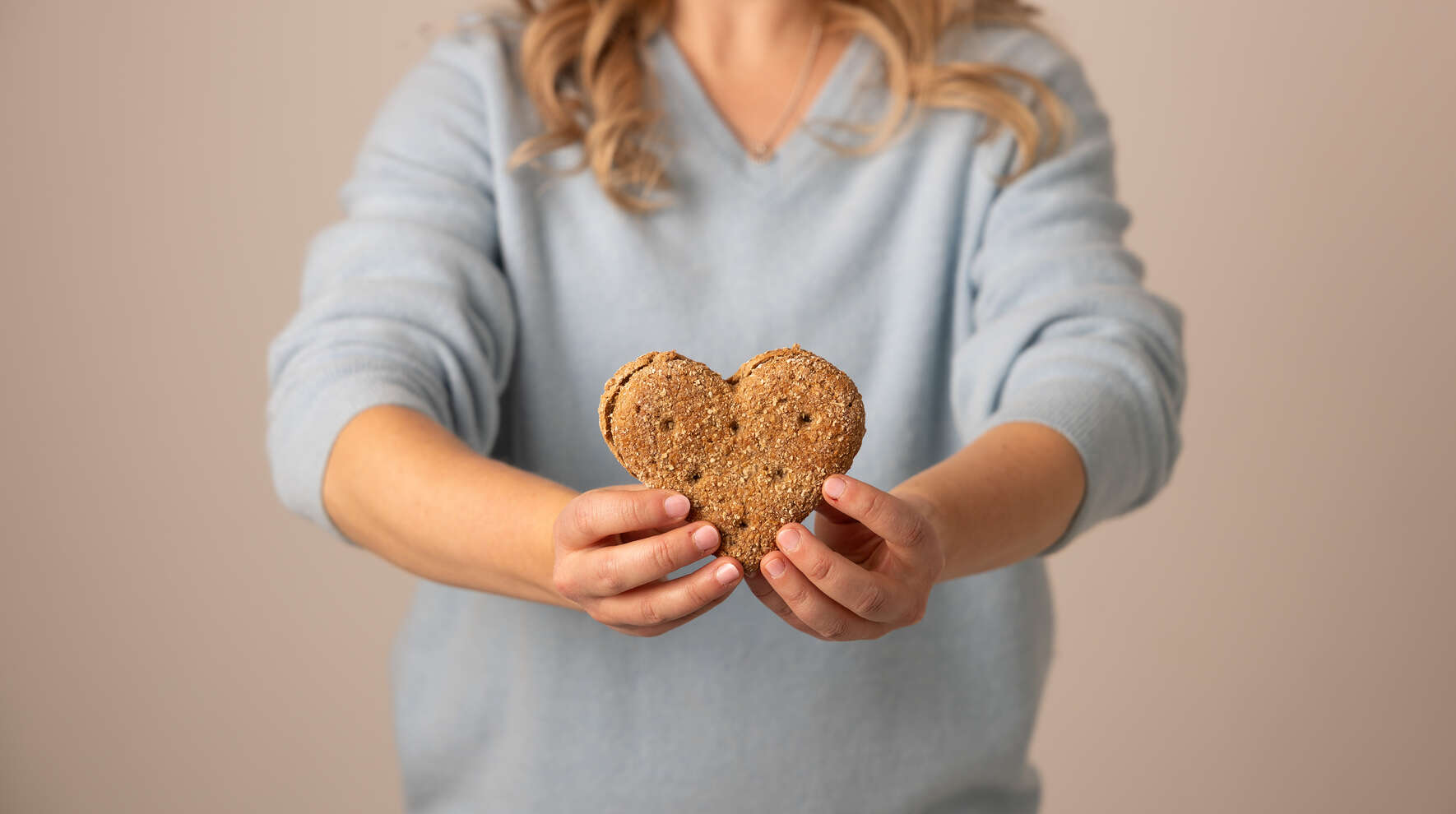 Kädet, jotka pitelevät sydämenmuotoista leipää.