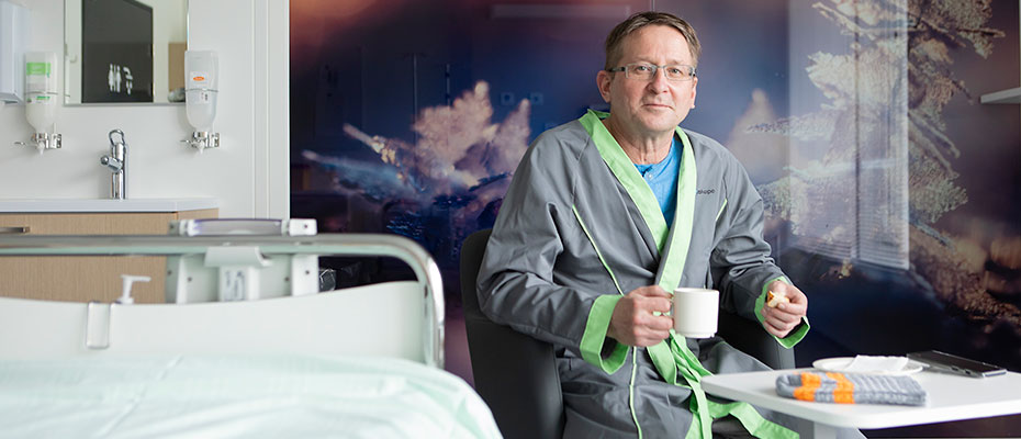 A male patient drinks coffee in a hospital ward.