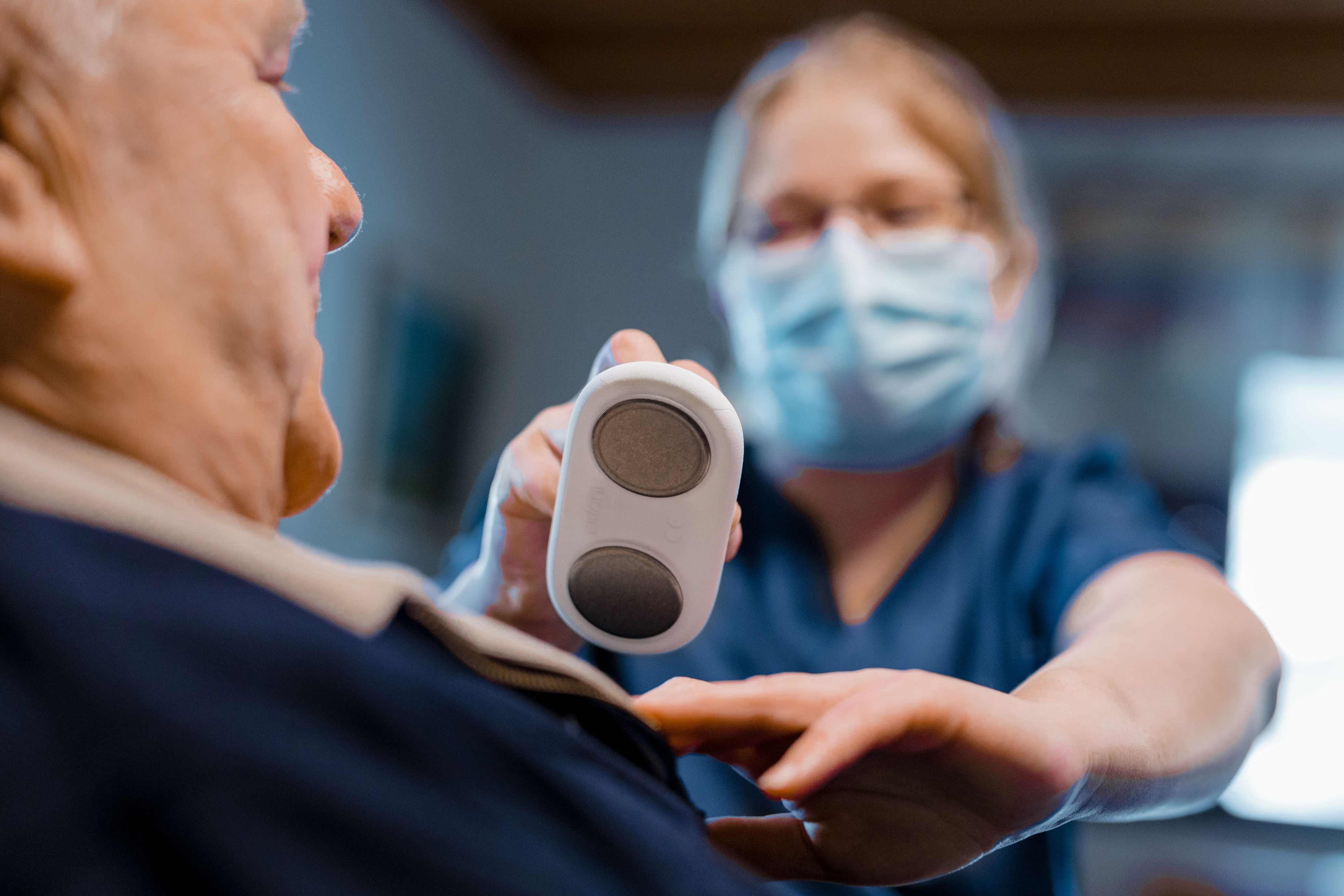 Hoitaja mittaamassa asiakkaan EKG:tä pienellä mittarilla.