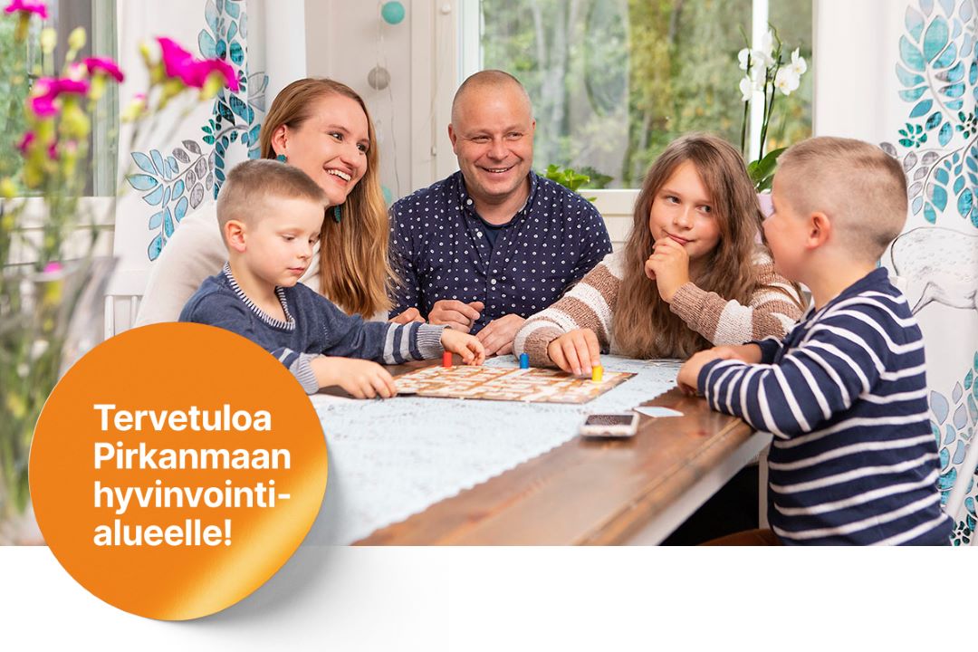 Kaksi lasta ja kolme aikuista istuu pöydän ääressä.