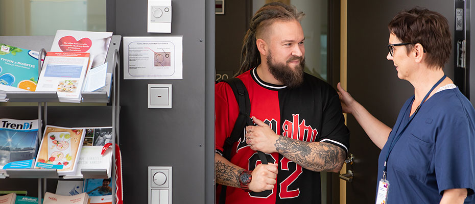 Miesasiakas ja hyvinvointialueen työntekijä katsovat toisiaan vastaanottotilojen ovella.