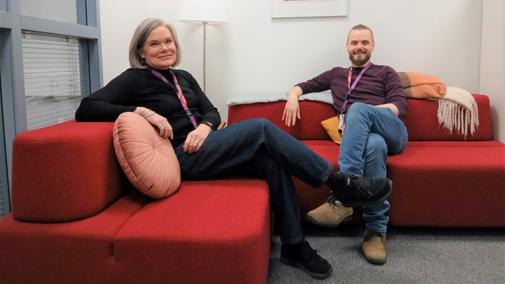 Nainen ja mies istuvat punaisella sohvalla.