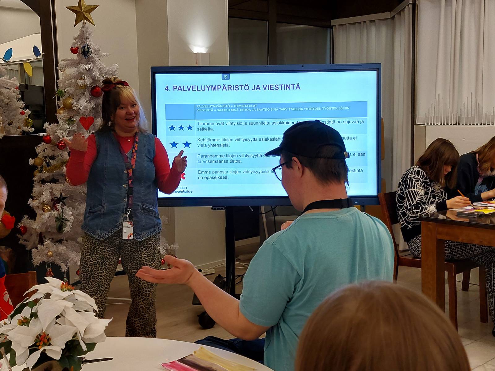 Henkilö selittää diaesityksen edessä vammaisille.