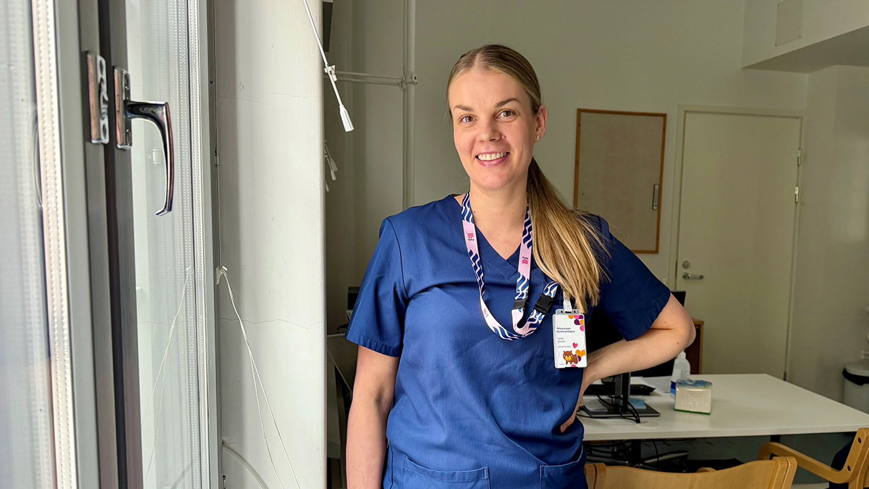 Sairaanhoitaja Carita Murtola seisoo vastaanottohuoneessa ikkunan vieressä.