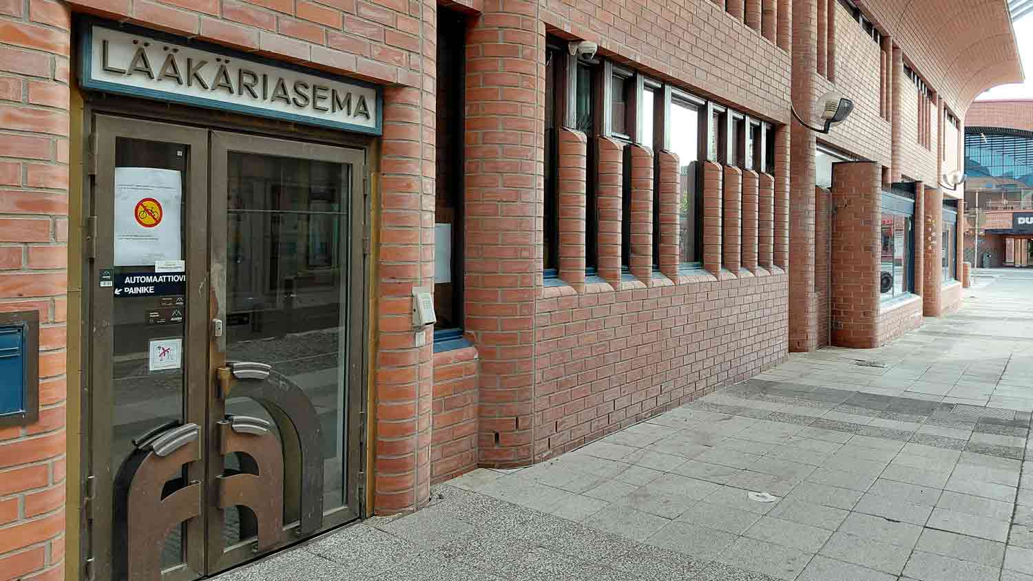 Punatiilisiä pyöreäkulmaisia rakennuksia ja sisäänkäynti, jossa lukee lääkäriasema
