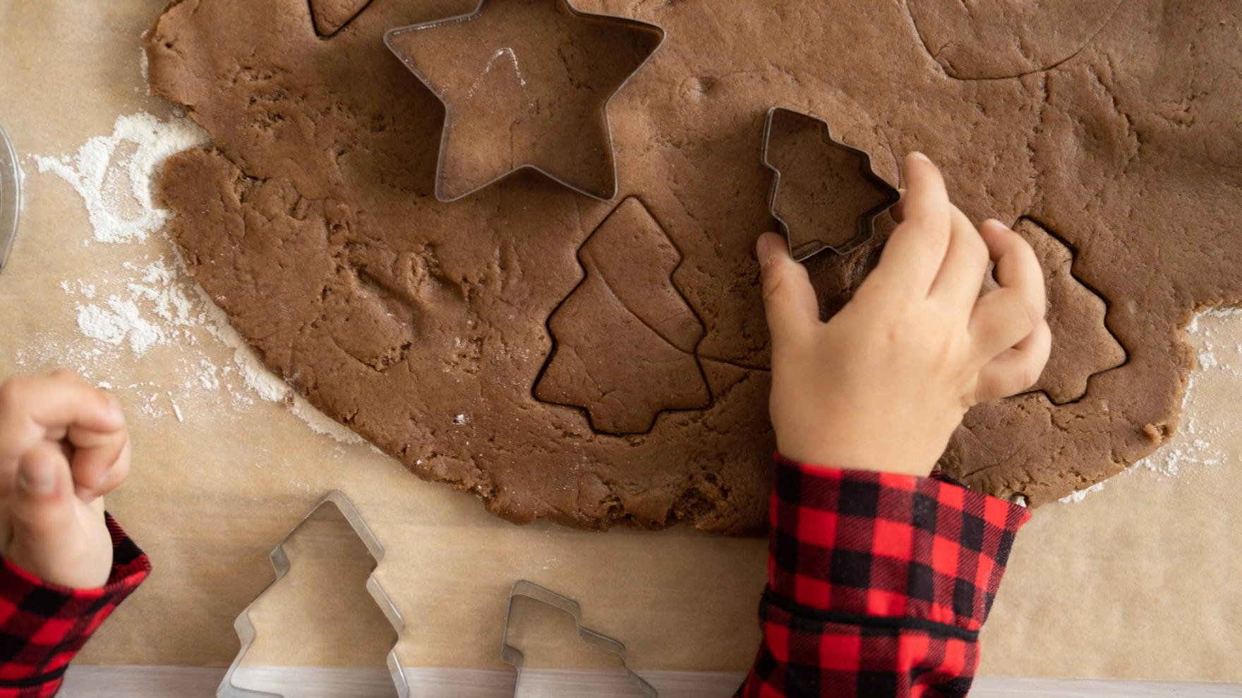 Piparkakkutaikina, josta lapsi on ottamassa muotilla piparkakkuja.
