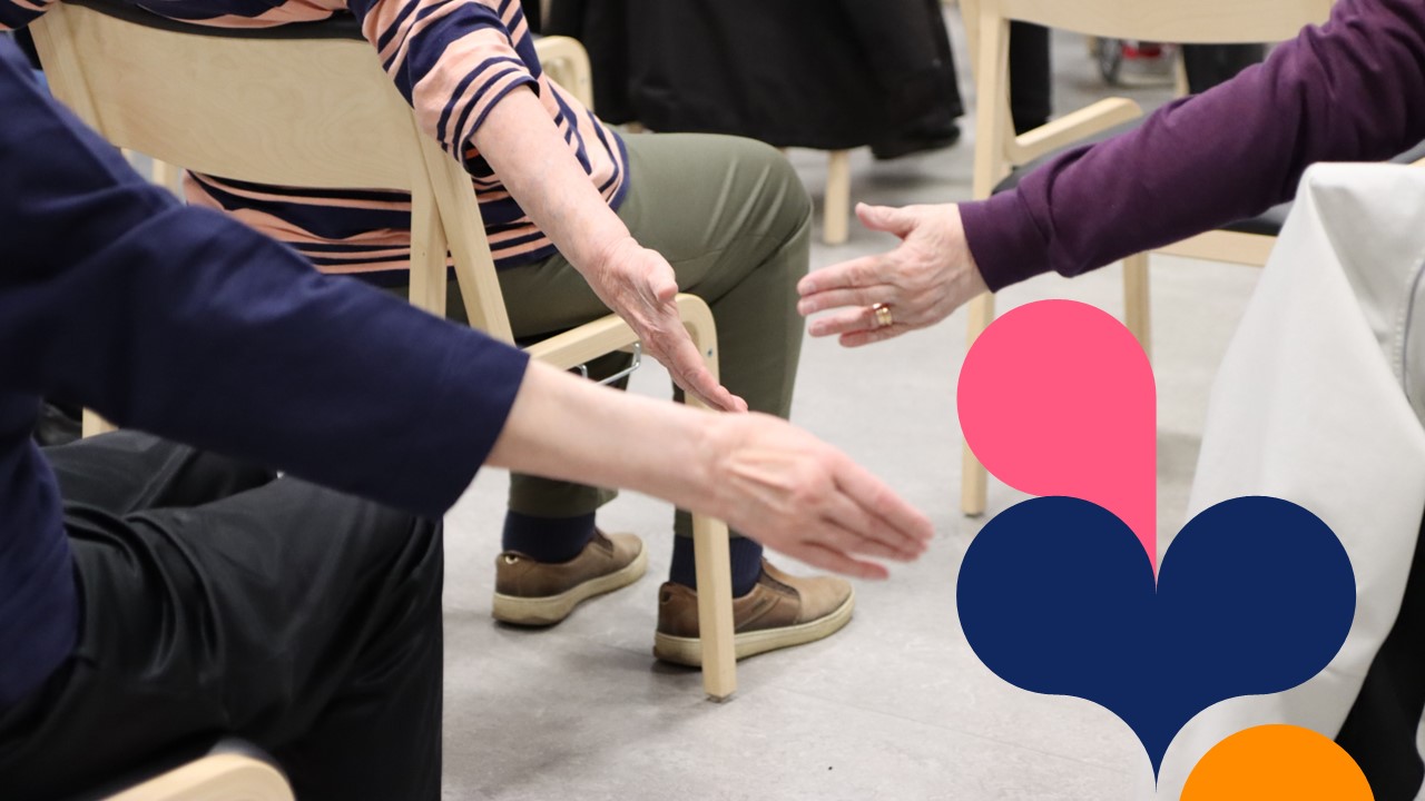 Ikääntyneet tekevät jumppaliikettä käsillään tuoleilla istuen.