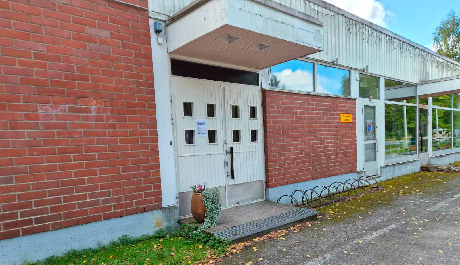 Valkoinen puinen pariovi punatiiliseen rakennukseen.