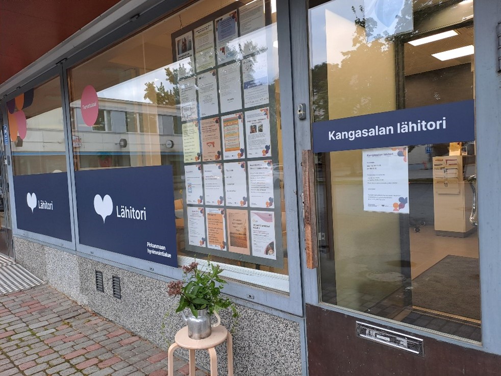 Kangasalan lähitorin etuovi ja ikkunat, joissa näkyy Pirkanmaan hyvinvointialuen teippauksia ja lähitorin ilmoituksia.