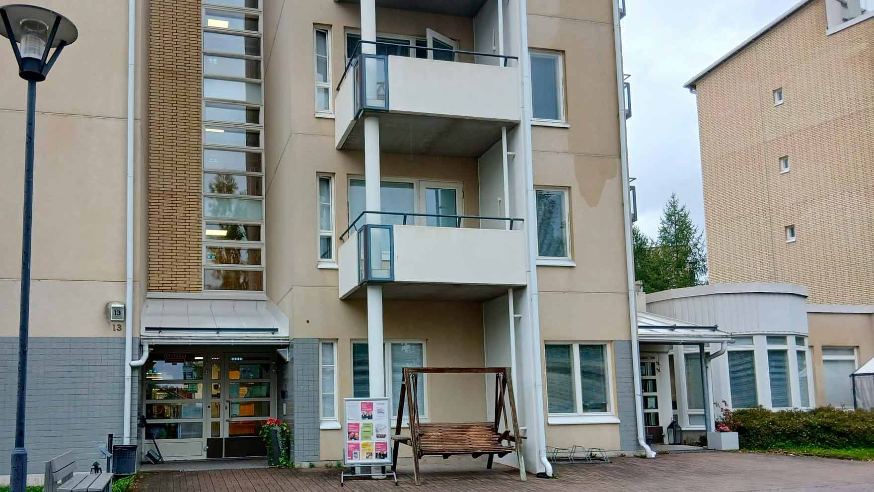 Kellertävä kerrostalo, johon on erilliset sisäänkäynnit rappukäytävään ja matalampaan siipiosaan.
