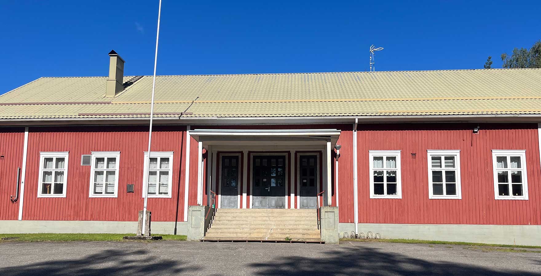 Punaisen puutalon julkisivu, keskellä sisäänkäynti.