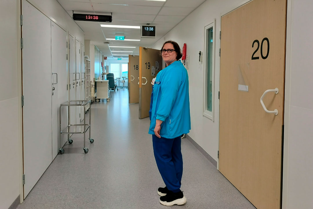 Maria seisoo ja hymyilee tehohoitoyksikön käytävällä. 