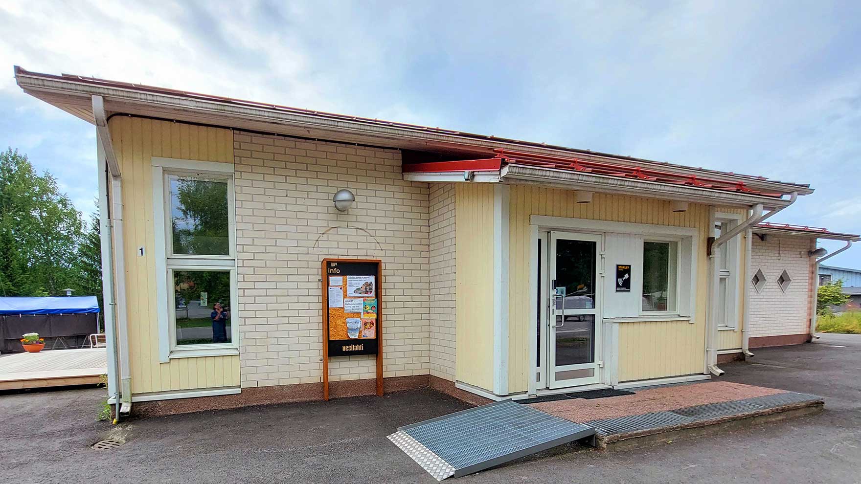 Pienehkö keltatiilinen rakennus, jonka sisäänkäynnin edessä on liuska.