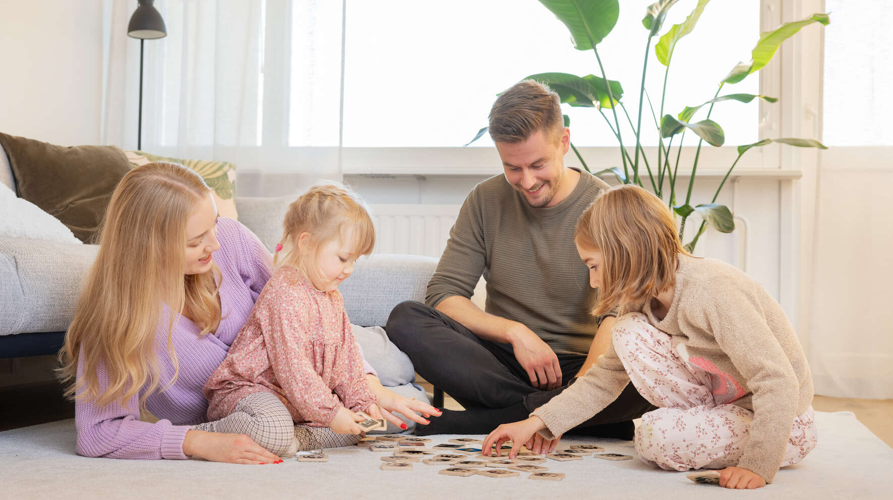 Perhe pelaa olohuoneen lattialla puisilla kuvakiekoilla.