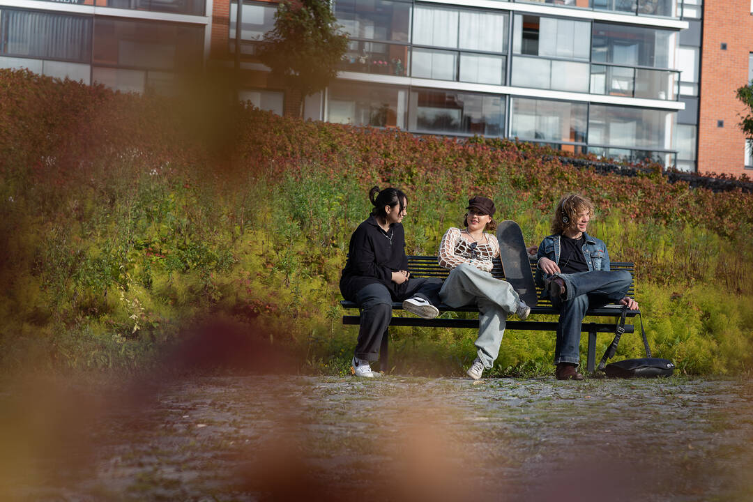Kolme nuorta istumassa puistonpenkillä