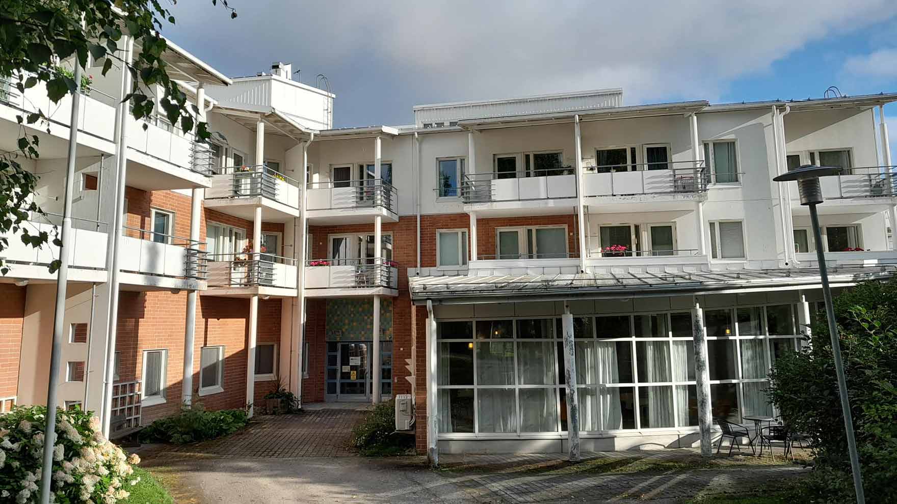 Kolmikerroksisen valko-punasävyisen kerrostalon sisäänkäynti.