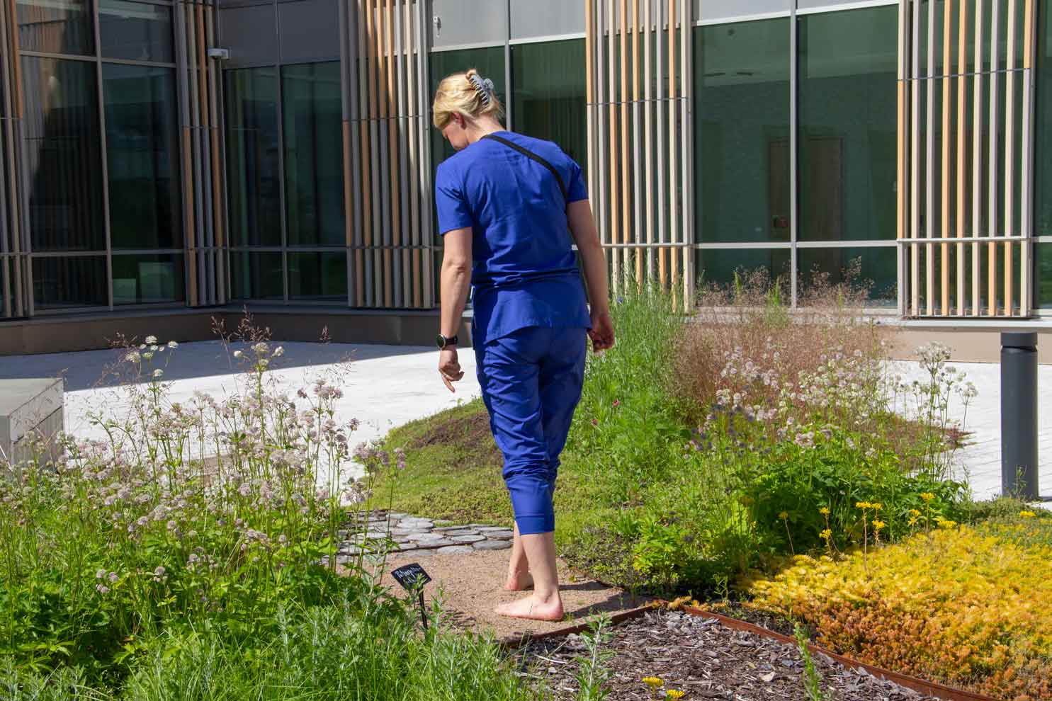 Katri Hatanpää kävelee paljasjalkapolkua pitkin, jossa on erilaisista pintoja.