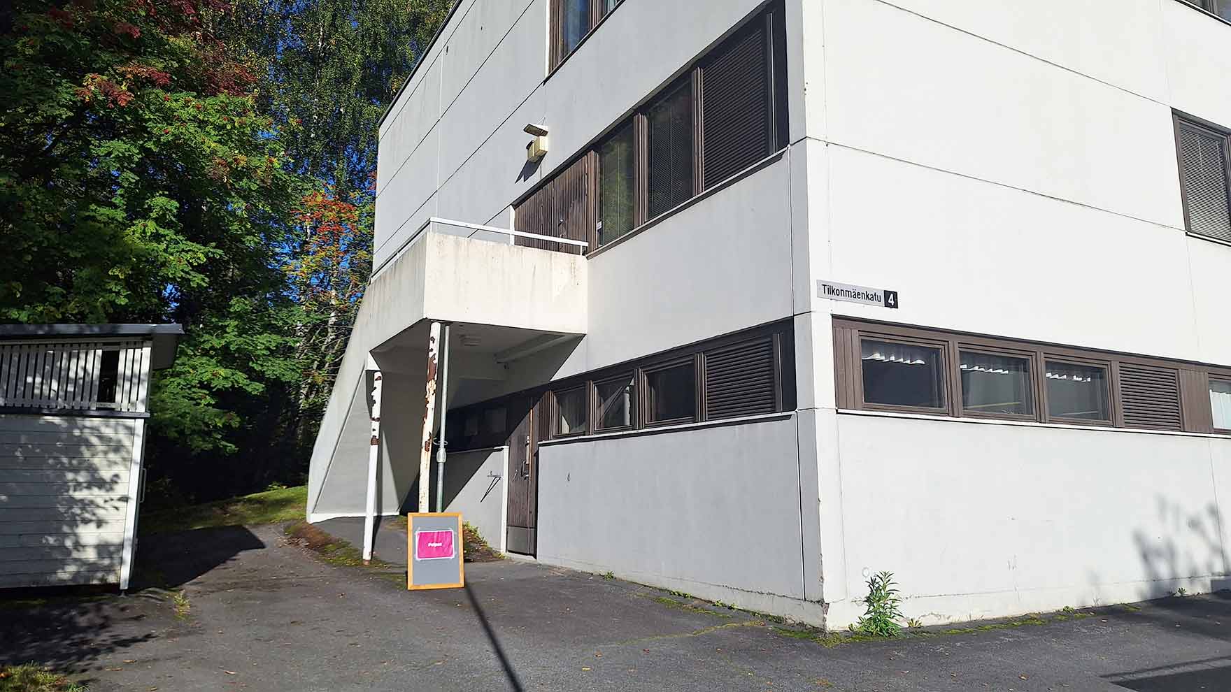 Kolmikerroksien vaalean talon sivustassa olevan tilan sisäänkäynti.