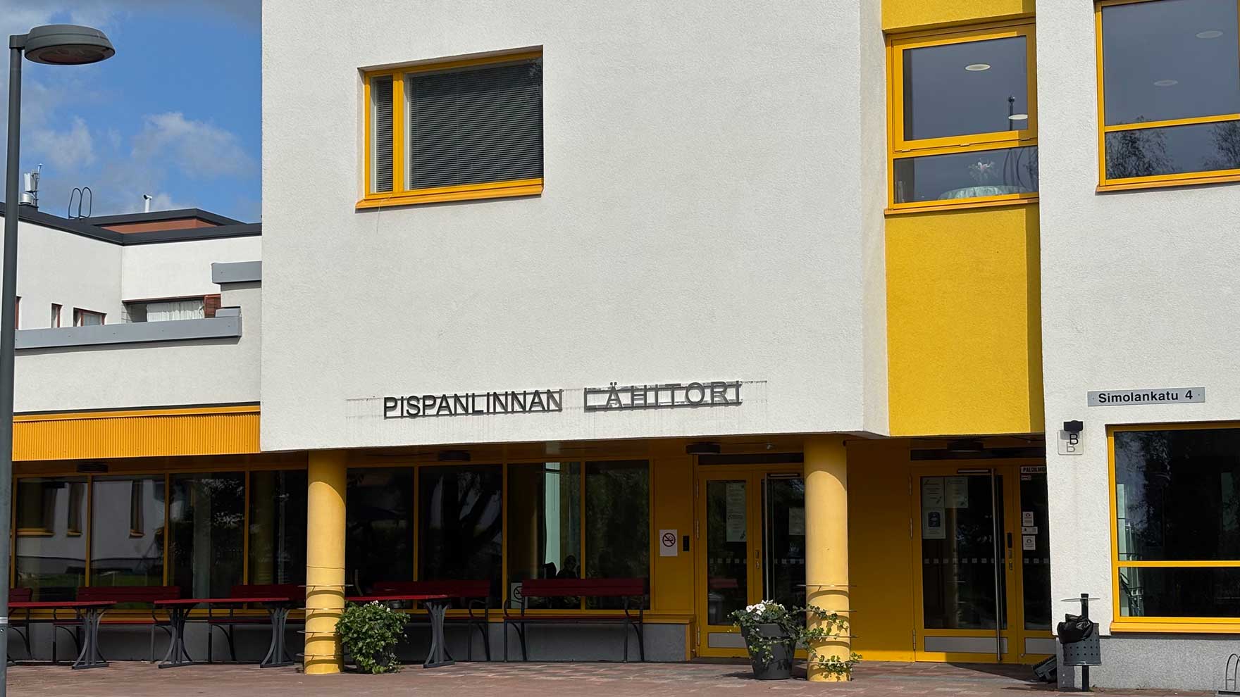 Valko-keltaisen talon sisäänkäynti, seinässä lukee Pispanlinnan lähitori.
