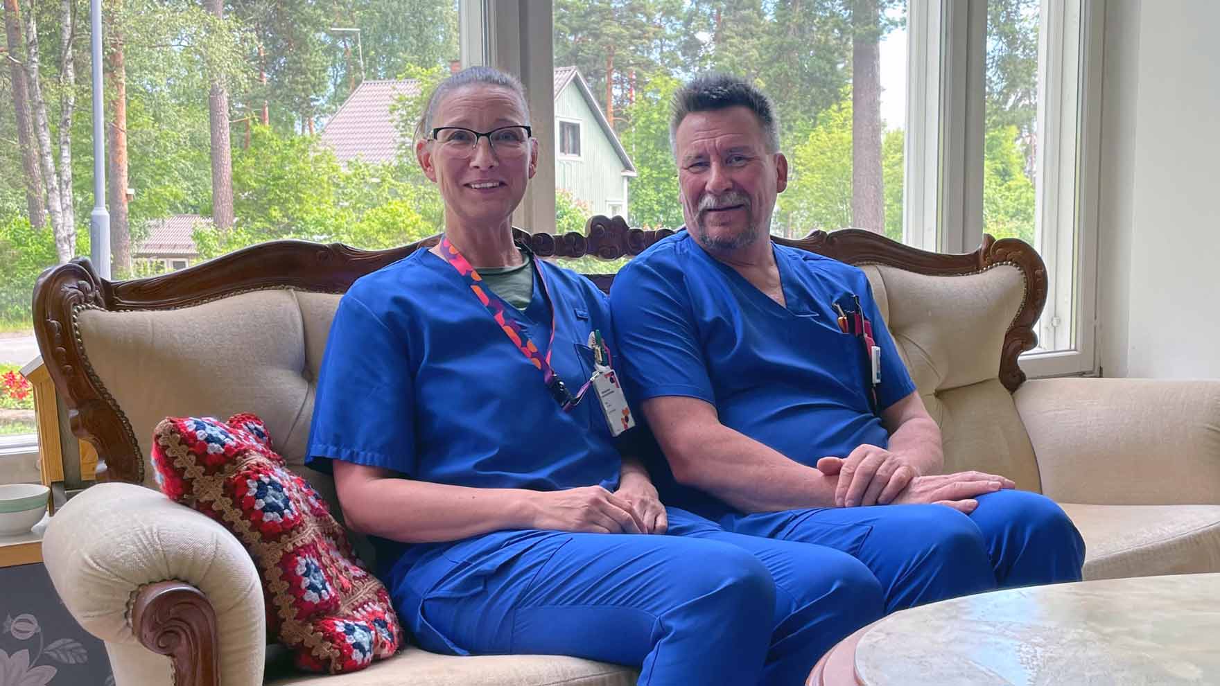 Lähihoitajat Sari ja Keijo istuvat sohvalla ja katsovat kameraan.