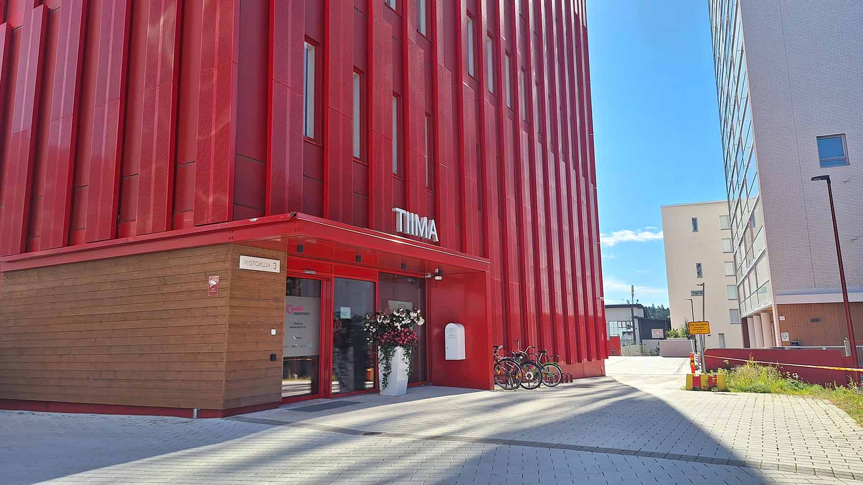 Sisäänkäynti moderniin punaiseen kerrostaloon.