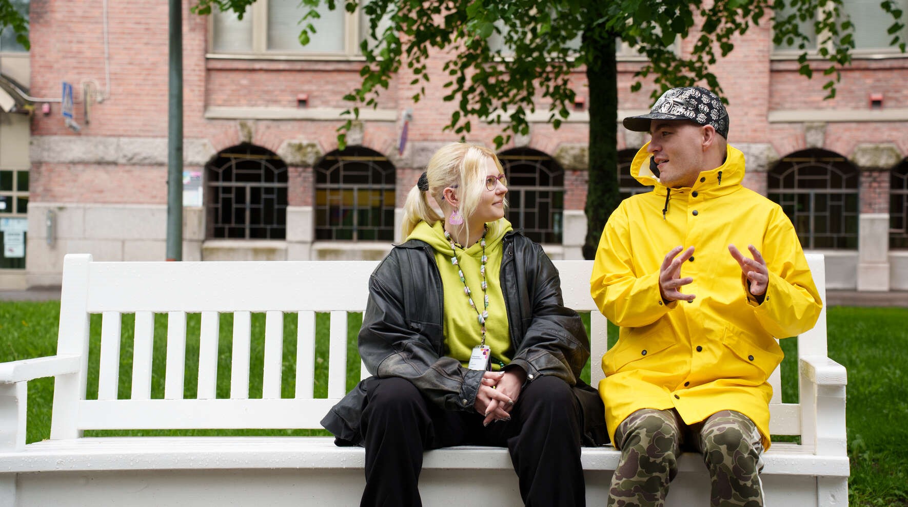 Vammainen ja Pirkanmaan hyvinvointialueen työntekijä istuvat ulkona penkillä ja juttelevat.