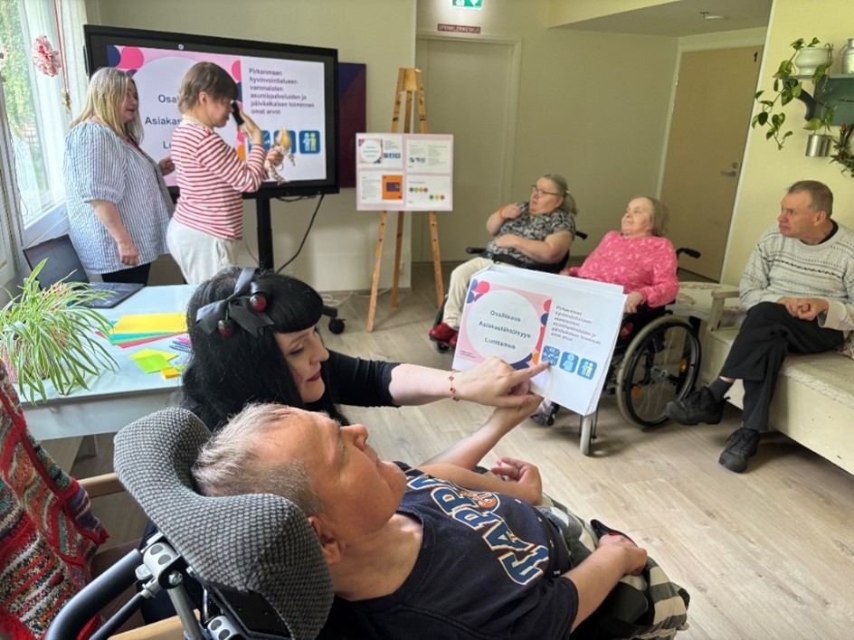 Jenny Pihl näyttää arvoihin liittyviä papereita vammaiselle.