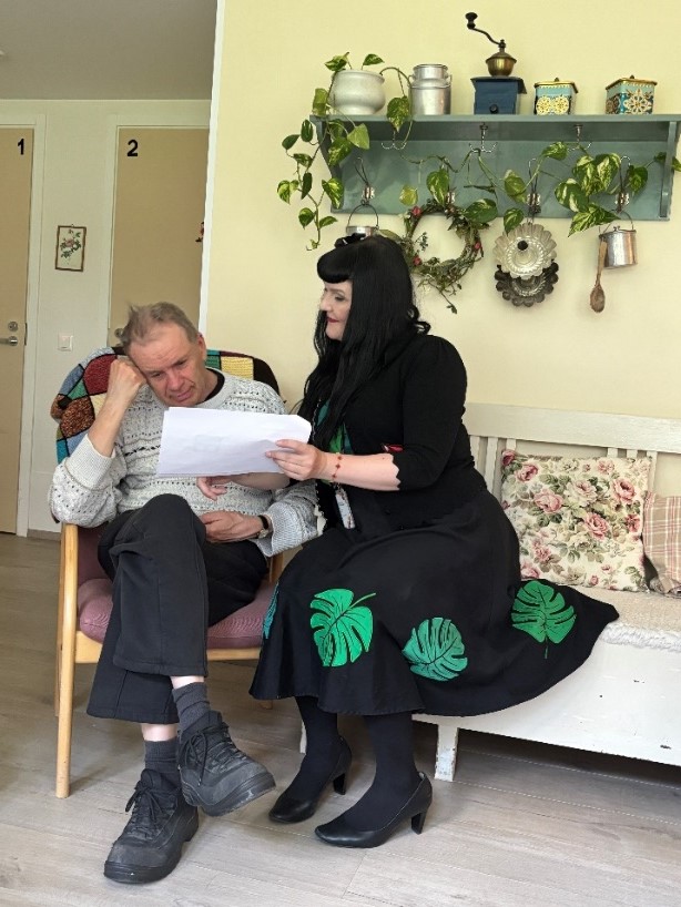 Jenny Pihl näyttää arvoihin liittyviä papereita vammaiselle.