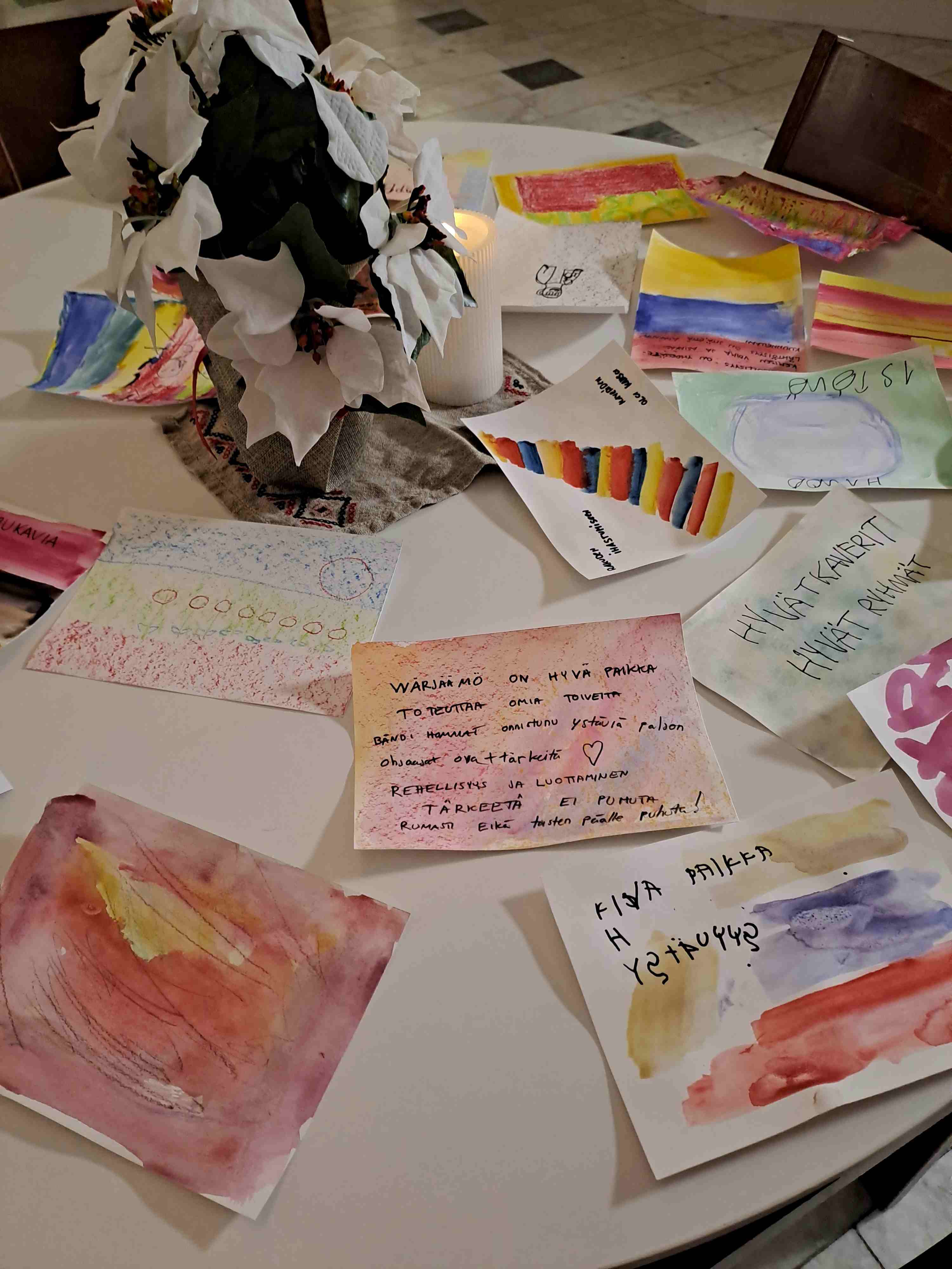 Pöydällä on hujan hajan vammaisten vesiväriteoksia ja runoja.