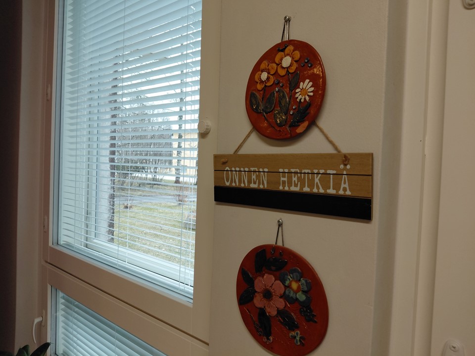 Venlantuvan ikkunan vieressä on kukkatauluja ja kyltti:"Onnen hetkiä".