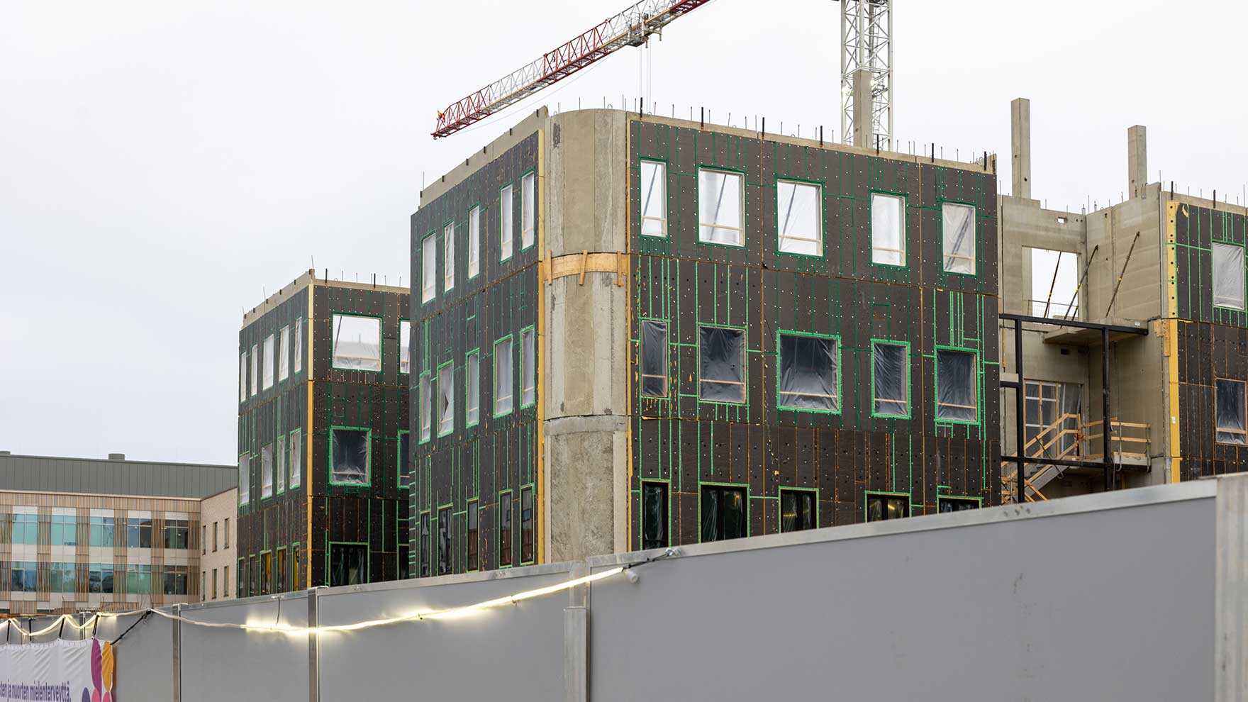 Valokuva kohoavasta Y-rakennuksesta työmaan laidalta otettuna.