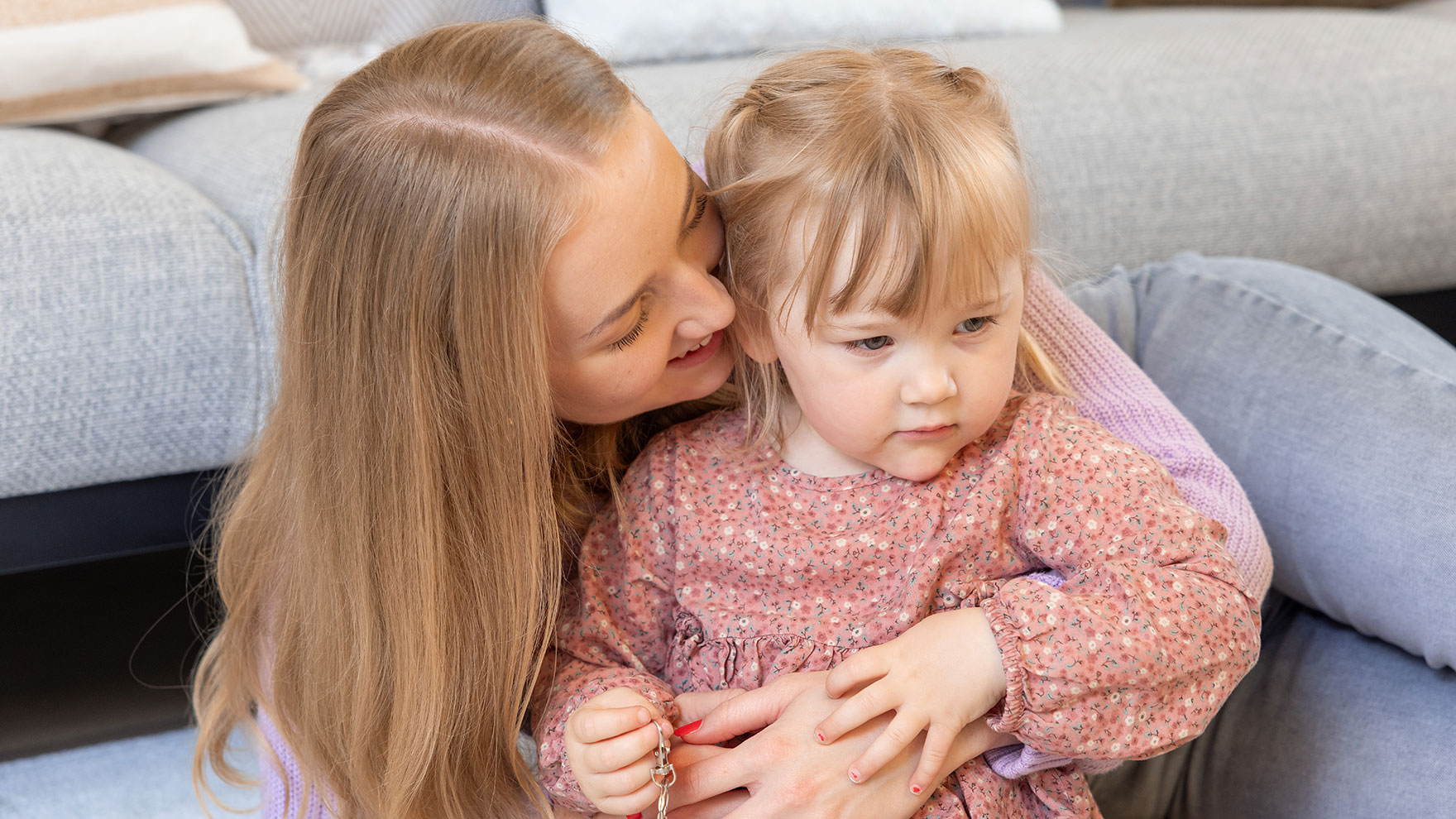 Äiti halaa lasta sohvalla.