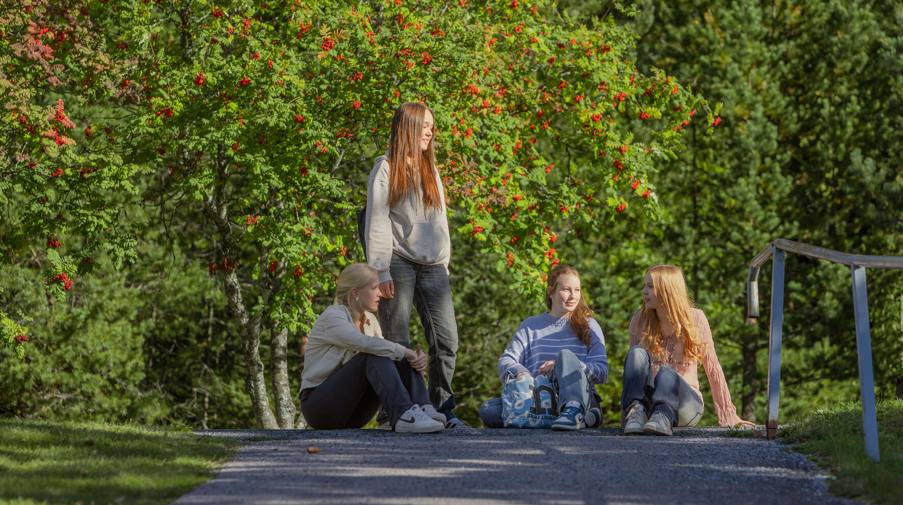 Neljä nuorta oleskelee ryhmässä pihatiellä.
